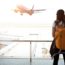 Traveler woman see the airplane at the airport window - Stopovers Paid By Carrier