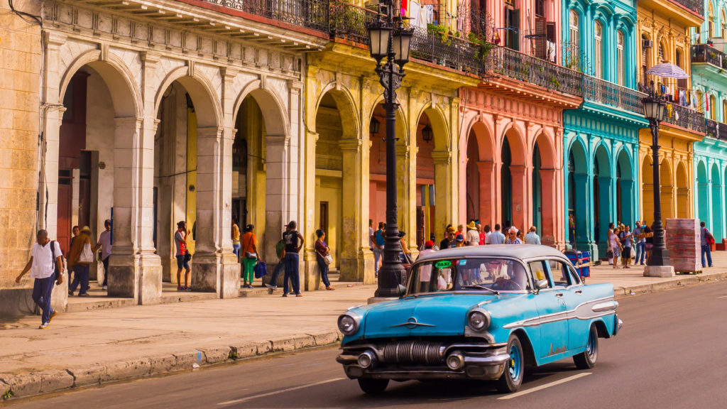 An old car driving through the historic part of Havana.